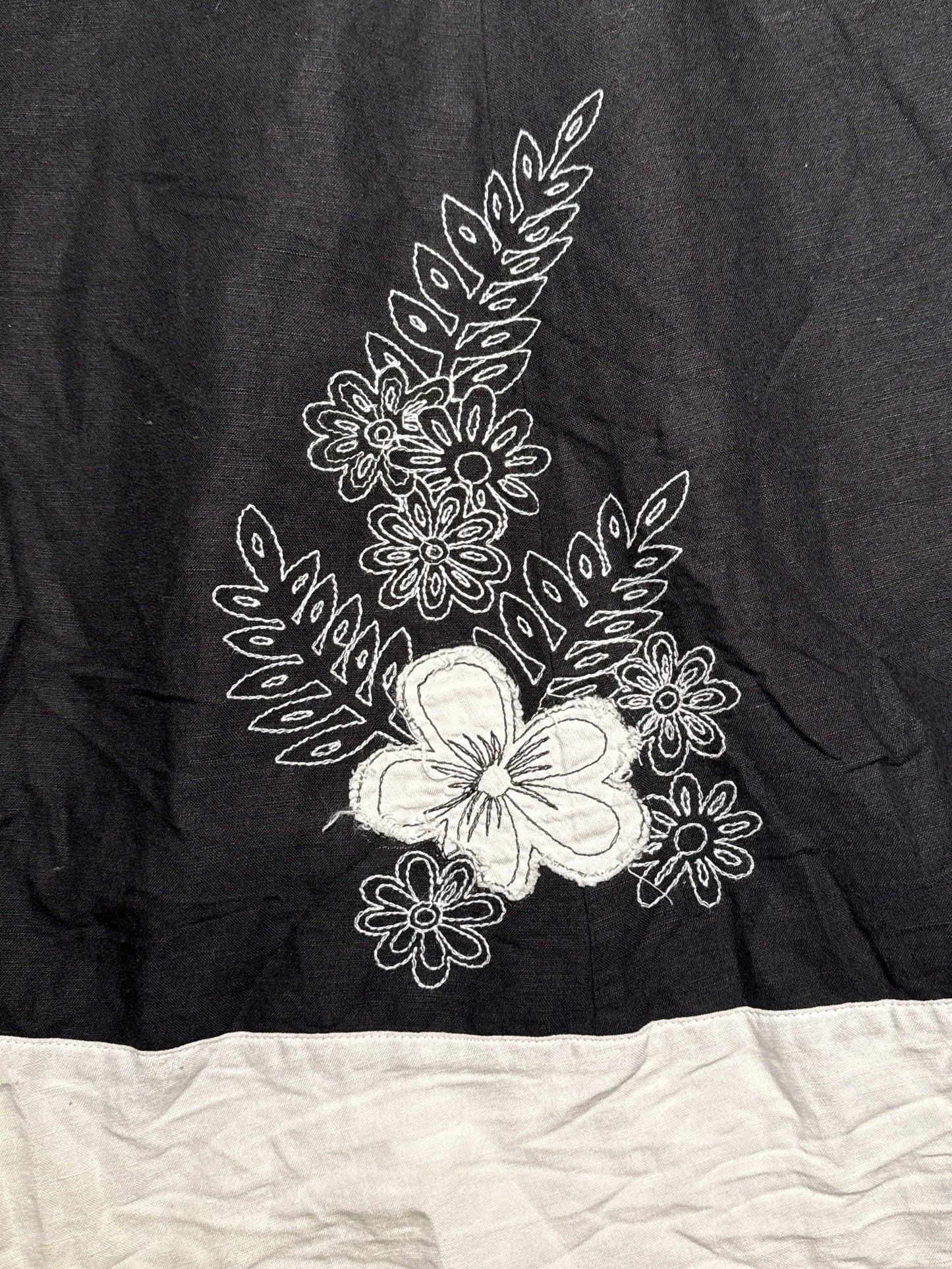 Black fabric with white floral embroidery on a beige surface