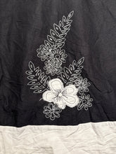 Load image into Gallery viewer, Black fabric with white floral embroidery on a beige surface
