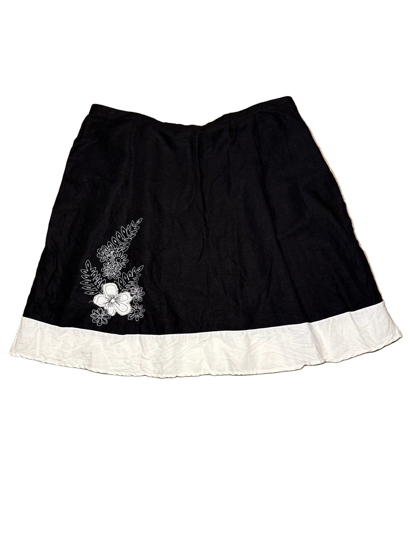 Black skirt with white floral embroidery on a white background