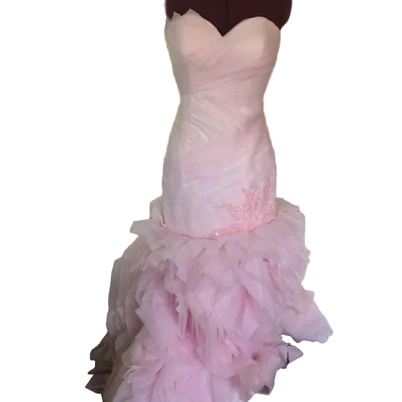 Pink mermaid-style dress on a mannequin against a light green wall.