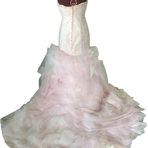 Pink wedding dress on a mannequin in a room with a chair and table.
