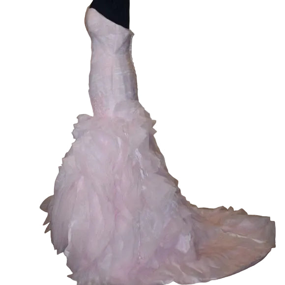 Pink wedding dress on a mannequin in a room with beige walls and wooden floor.