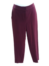 Load image into Gallery viewer, A pair of burgundy St. John women's pants displayed on a mannequin against a background of a brick wall and wooden fence.
